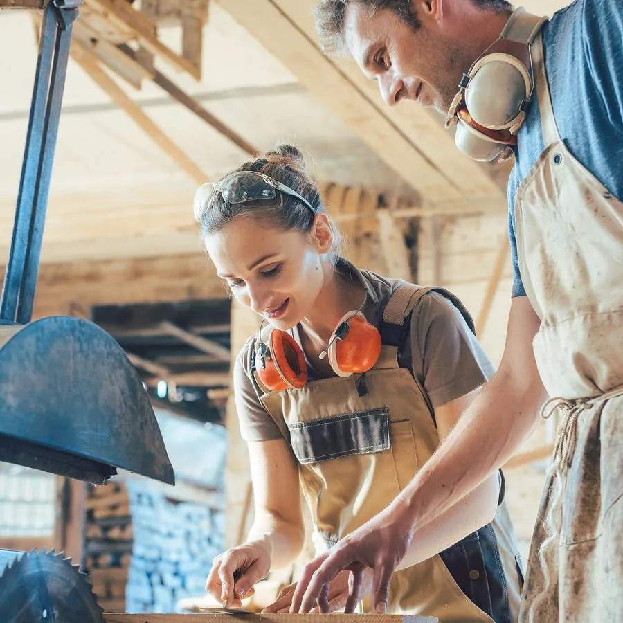 Zwei Handwerkende bei der Arbeit in einer Werkstatt